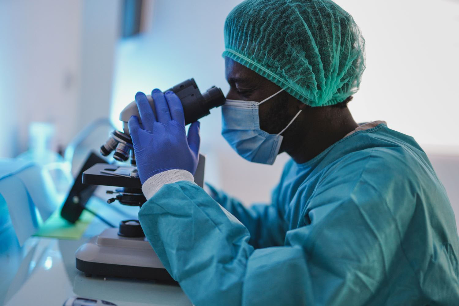 man looking in microscope working inside hospital laboratory