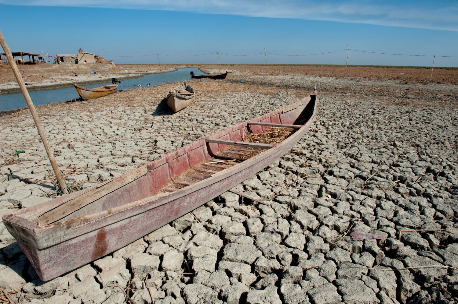 A traditional Marsh Arab canoe known as a Mashoof abandoned on the dry cracked earth of the southern marshes of Iraq during a hash summer drought.