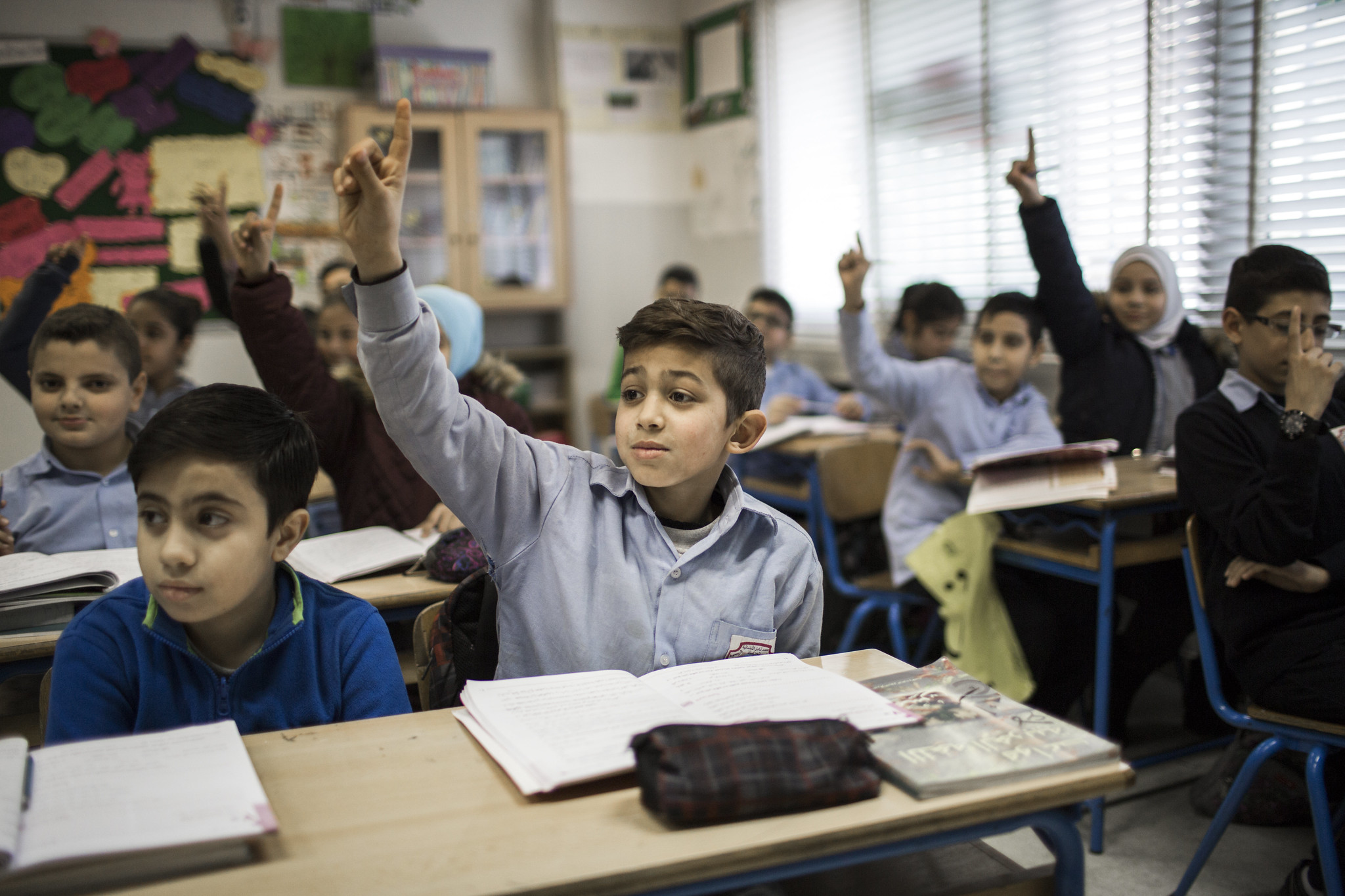 Syrian children in class room raising hands