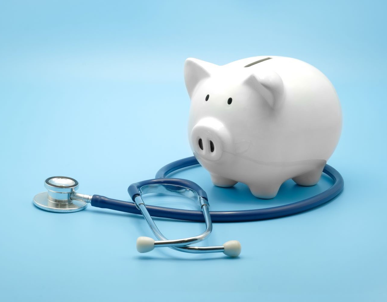 Piggy bank with stethoscope isolated on light blue background with copy space. 