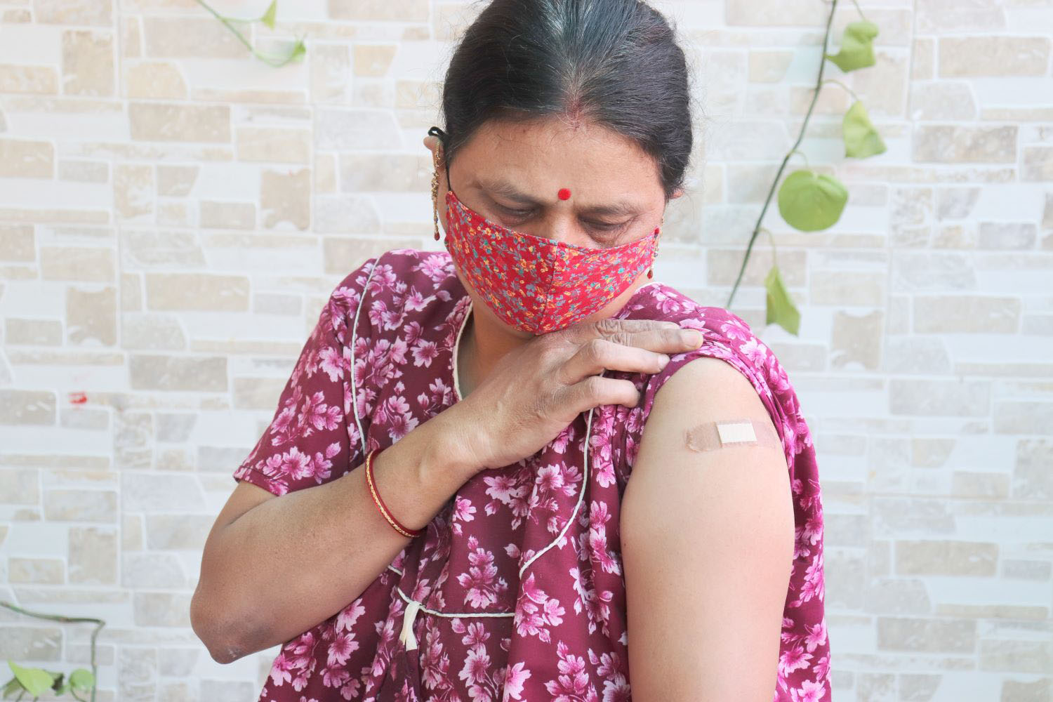 woman looking at bandage applied after getting vaccination