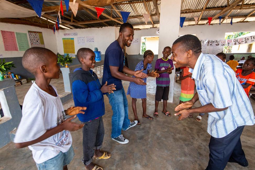 Two teachers lead students in a game at a school in Liberia