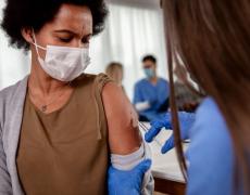 An image of a nurse giving the Covid vaccine to a female patient.