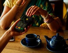An image of an Indian woman using a credit card to pay. 