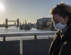 A commuter wearing a face mask walks over London Bridge into the city